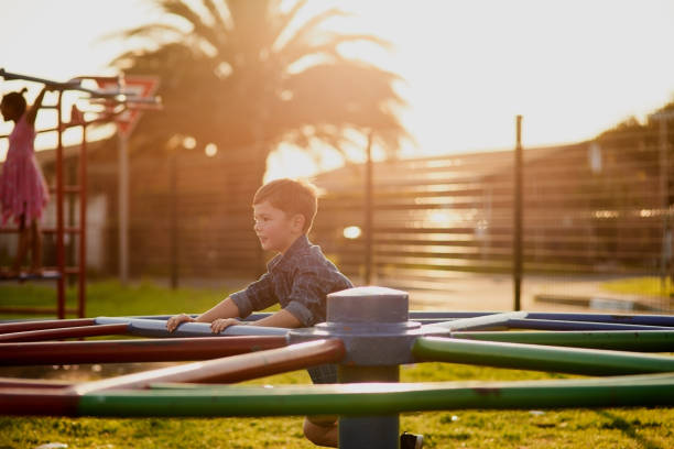 Cropped shot of an adorable little boy playing with the merry go round at a playground outside