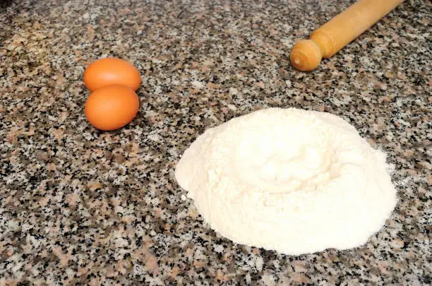 Photo of homemade cake, nest of flour eggs and rolling pin on marble background