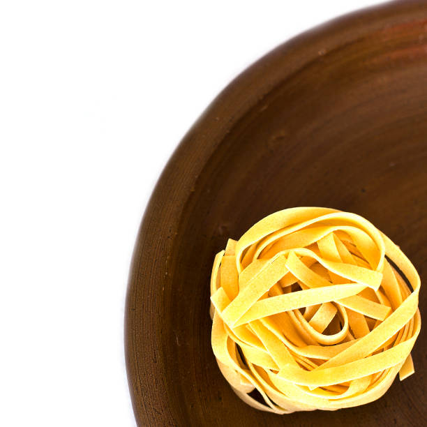 Uncooked tagliatelle on a ceramic plate. Isolated