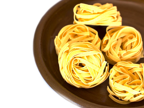 istock Uncooked tagliatelle on a ceramic plate. Isolated 1039656878