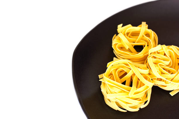 istock Uncooked tagliatelle on a ceramic plate. Isolated 1039656986