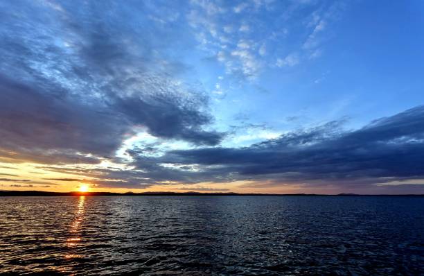 istock dark blue evening sky over the lake, orange sun 1039661194