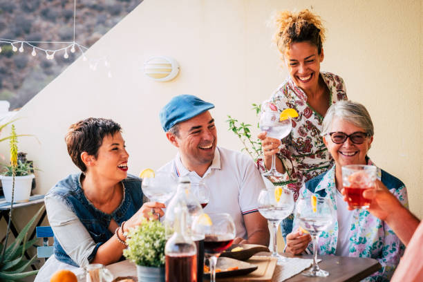 group of adults mixed ages from 40 to 70 celebrate together at home in the terrace with food and wine. friendship together people concept having fun and nice lifestyle smiling a lot and live happy laughing - food vegan food gourmet vegetarian food imagens e fotografias de stock