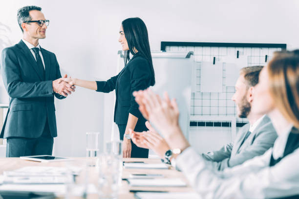 istock boss shaking hand of asian manageress at conference hall while colleagues clapping 1039664370