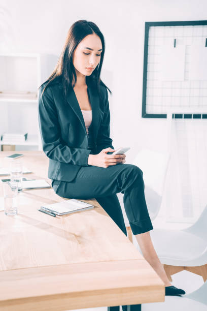 istock asian businesswoman using smartphone while sitting on table at office 1039668676