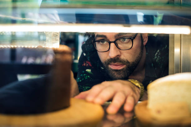istock Man getting cake out of the display fridge 1039697154