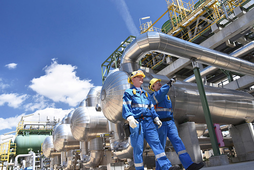 Grupo de trabajadores industriales en una refinería - equipo y maquinaria de procesamiento de aceite photo