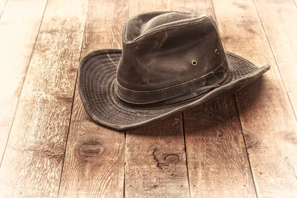weathered outback hat on rustic red barn wood, sepia toned image