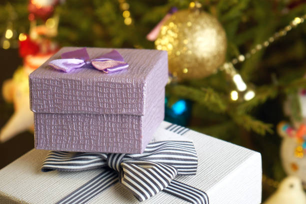 Gift boxes with bows on the lids under a Christmas tree in New Year Eve