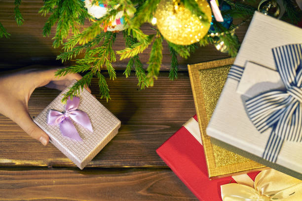 Girl's hand picks up or puts a little gift box from under a Christmas tree