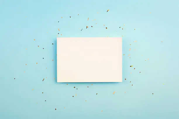 white card on a blue background. gold confetti. blank for postcard for birthday, Christmas, new year, celebration.