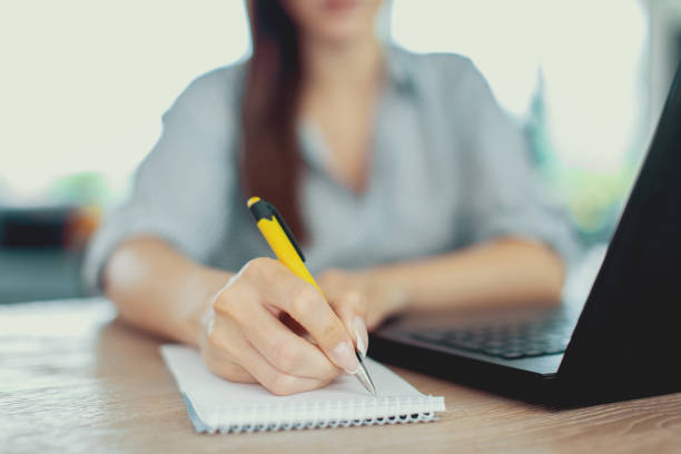 istock Young woman writing notes at laptop closeup 1039770818