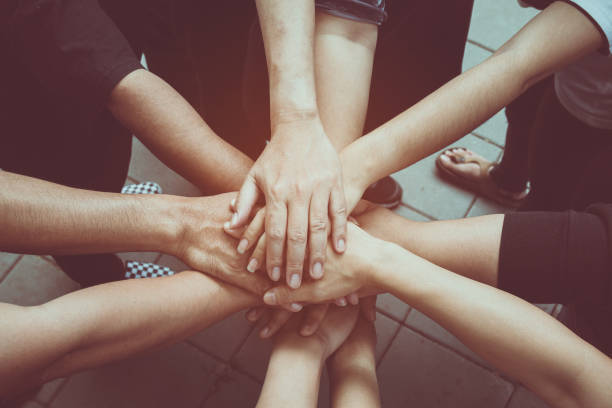istock Teamwork concept; many people standing hands together in field before starting competition game 1039778392