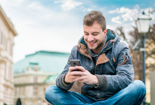 istock Satisfied  young man holding his phone while texting 1039782536