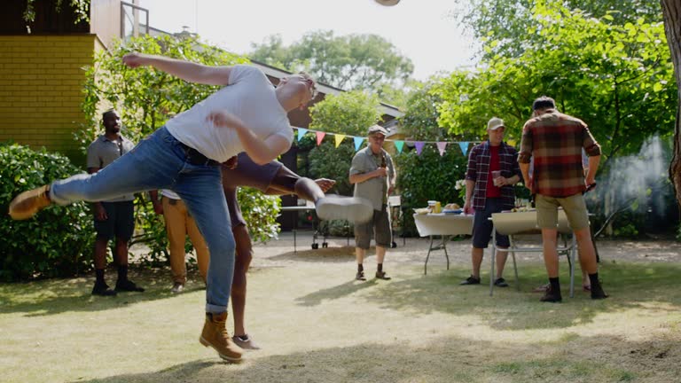 Men friends playing soccer and barbecuing in backyard. MS, slow motion.