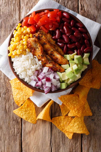 pollo a la plancha con arroz, aguacate, frijoles, tomates, maíz y cebolla close-up. vista superior vertical - grilled chicken chicken corn salsa fotografías e imágenes de stock