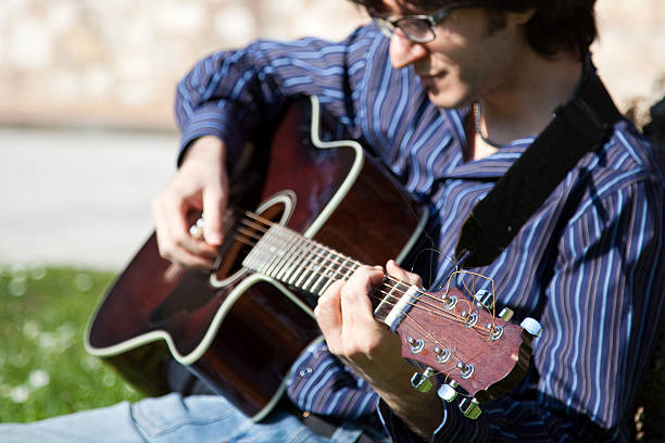 istock Young Man Playing Guitar in a Green Lawn 103980321
