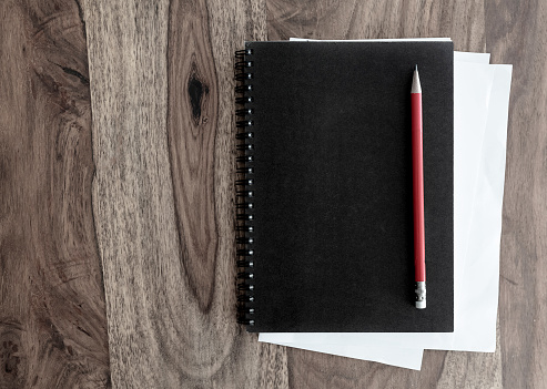 directly above shot of black spiral notebook and pen on wooden table