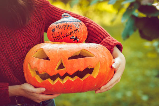 istock Girl holding jack o' lantern and painted pumpkin 1039840318