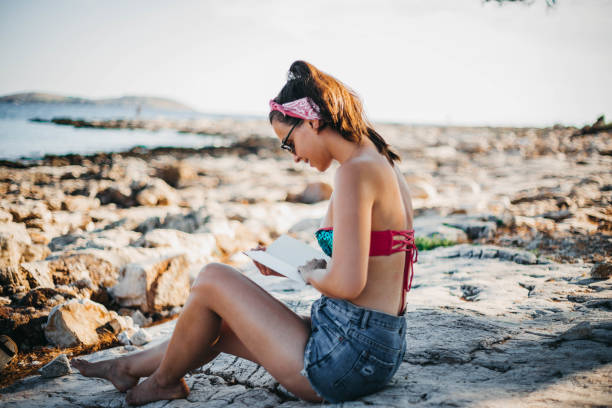 istock Women reading a book on a rock 1039844240