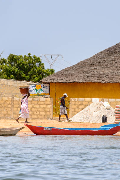 Unidentified Senegalese woman carries a basin on her head on the coast of the Casamance river CASAMANCE RIVER, SENEGAL - APR 29: Unidentified Senegalese woman carries a basin on her head on the coast of the Casamance river casamance river stock pictures, royalty-free photos & images