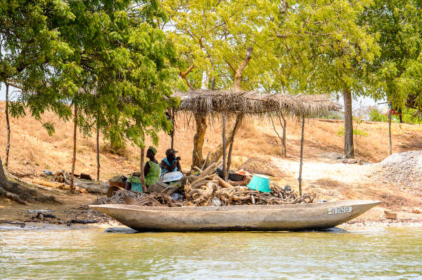 Unidentified Senegalese women sit under the canopy on the coast of the Casamance river CASAMANCE RIVER, SENEGAL - APR 29: Unidentified Senegalese women sit under the canopy on the coast of the Casamance river casamance river stock pictures, royalty-free photos & images