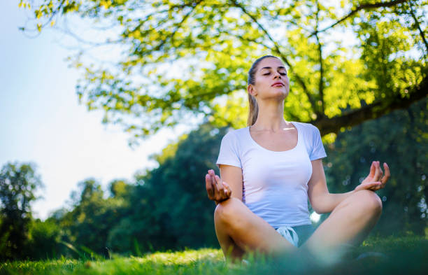 piękna kobieta medytująca w parku miejskim - spirituality yoga zen like meditating zdjęcia i obrazy z banku zdjęć