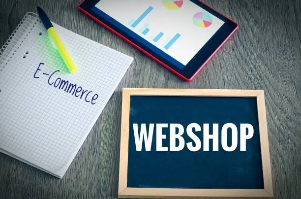 Plate with the inscription Webshop and E-Commerce  with a tablet Graphs and statistics and block to illustrate the increase in sales of an online shop
