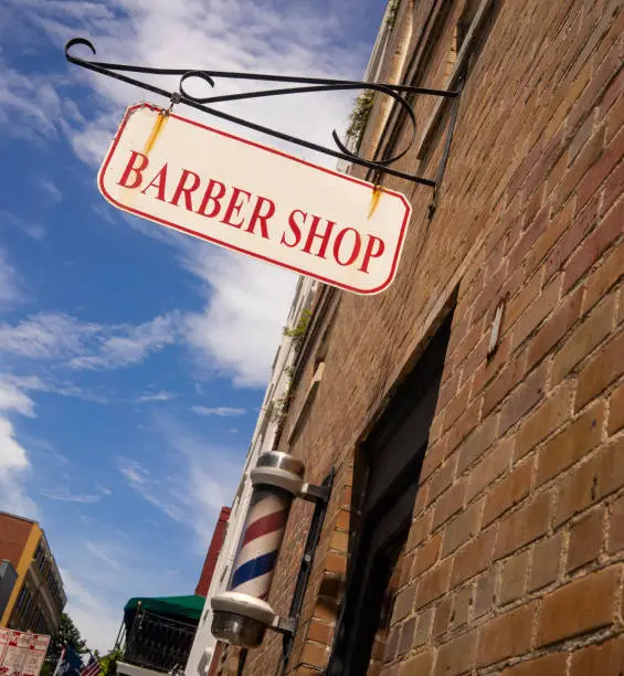 A white and red barber shop sign has rust above the striped pole