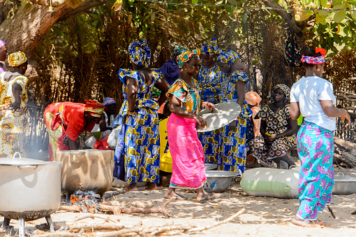 KASCHOUANE, SENEGAL - APR 29, 2017: Unidentified Diola women in traditional clothes cook on the street in Kaschouane village. Diolas are the ethnic group predominate in the region of Casamance