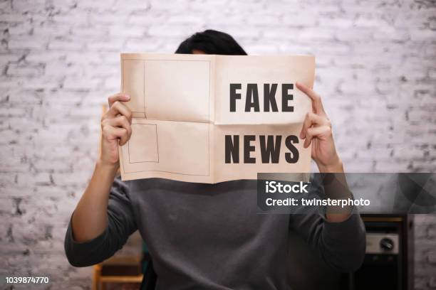Young Male Businessman Reading Fake And Misled News On Traditional Press Newspaper Stock Photo - Download Image Now