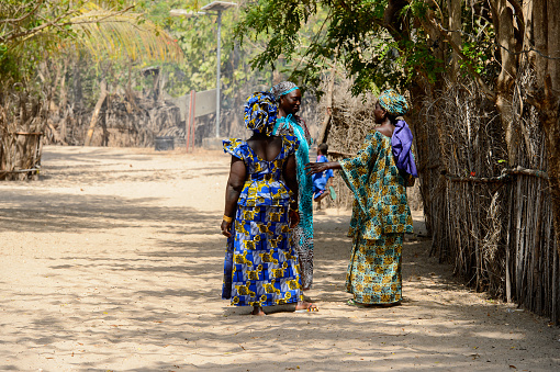 KASCHOUANE, SENEGAL - APR 29, 2017: Unidentified Diola women in traditional clothes walk along the street in Kaschouane village. Diolas are the ethnic group predominate in the region of Casamance