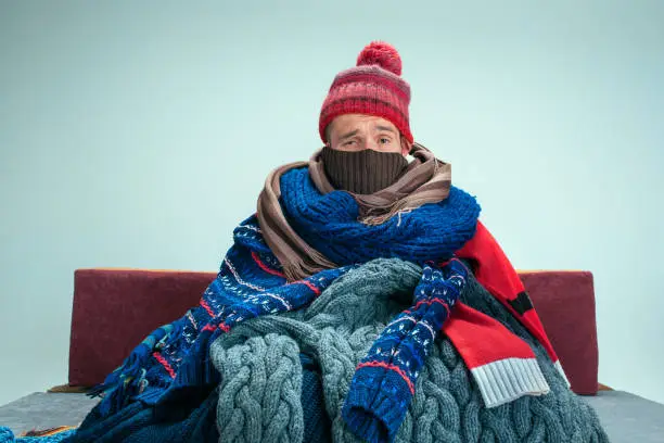 Photo of Bearded Man with Flue Sitting on Sofa at Home. Healthcare Concepts.