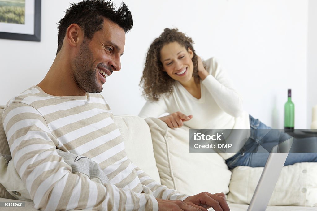 Junges Paar sitzt auf sofa mit laptop zu Hause - Lizenzfrei Arbeiten Stock-Foto