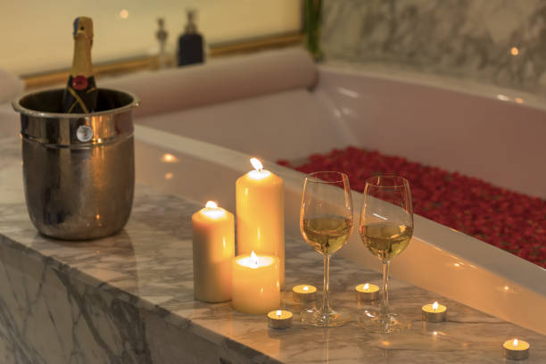 zwei gläser champagner mit kerze in der nähe von whirlpool. valentines hintergrund. romantik-konzept. - soaking tub stock-fotos und bilder