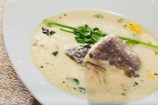 istock Creamy soup with white fish hake served with  greens at plate 1039915054