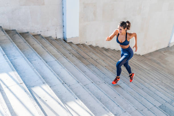 photo of sports woman running up outdoor stairway - determination running staircase jogging imagens e fotografias de stock