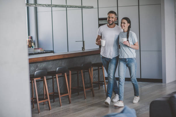istock smiling couple with coffee cups in kitchen at home 1039924066