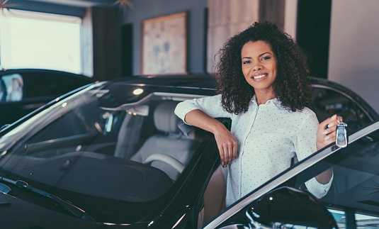 Smiling woman holding the car keys of his new car