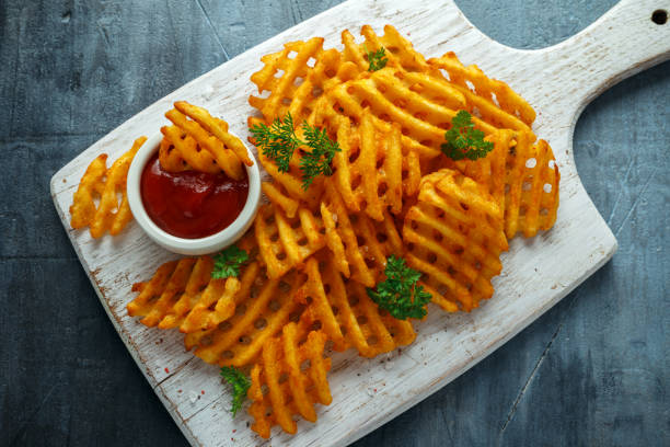 Crispy Potato Waffles Fries with Ketchup on white wooden board Crispy Potato Waffles Fries with Ketchup on white wooden board. Potato Waffle stock pictures, royalty-free photos & images