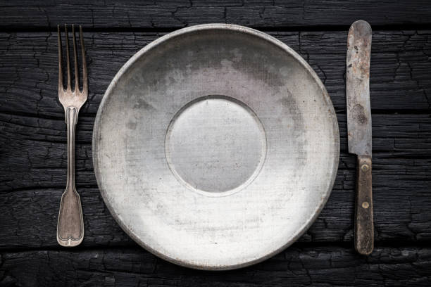 Empty plate with silverware on black background