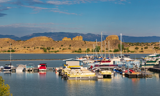 Pueblo, CO, USA-16 July 18: Colorful boats in foreground, rock formations in midground, a distant mountain range, and wispy clouds above--Pueblo State Park.