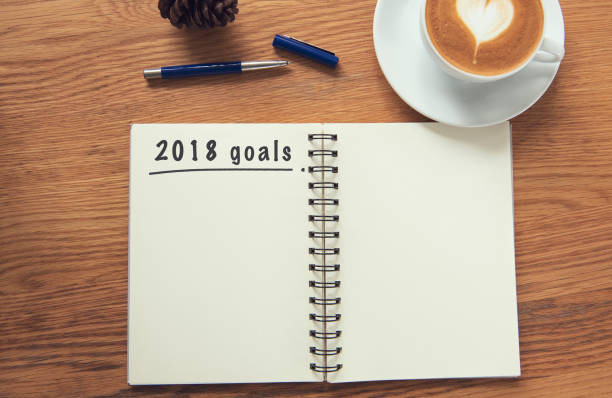 istock Coffee cup and notebook with goals 2019 on rustic desk from above, planner and checklist concept. 1039991774