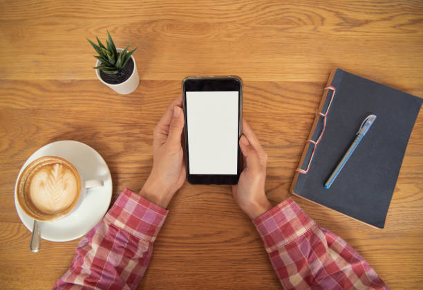 istock hand holding mobile phone with blank white screen in cafe. mockup advertising. 1039991822