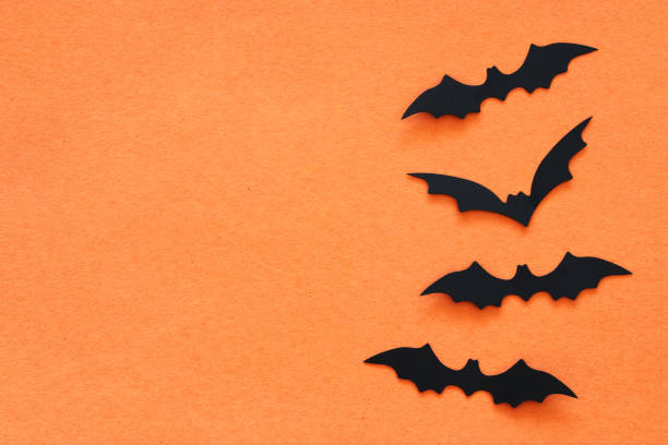 istock Halloween holiday concept. Black bats over orange background. Top view, flat lay. 1039995806