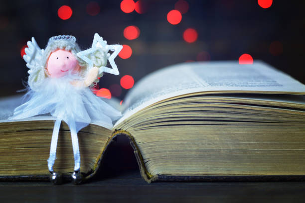 Angel sitting on the book and holding a star