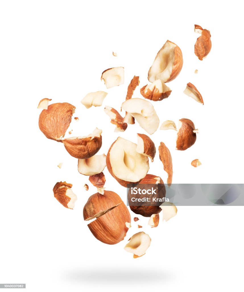 Hazelnuts crushed into pieces, frozen in the air on a white background Hazelnut Stock Photo