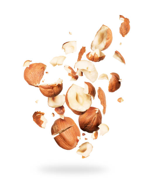 Hazelnuts crushed into pieces, frozen in the air on a white background Hazelnuts crushed into pieces, frozen in the air on a white background hazelnut stock pictures, royalty-free photos & images