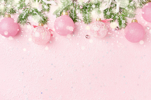 Christmas border of New Year's ornaments, fir and snow on pastel pink. Winter holidays, New Year background with copy space.
