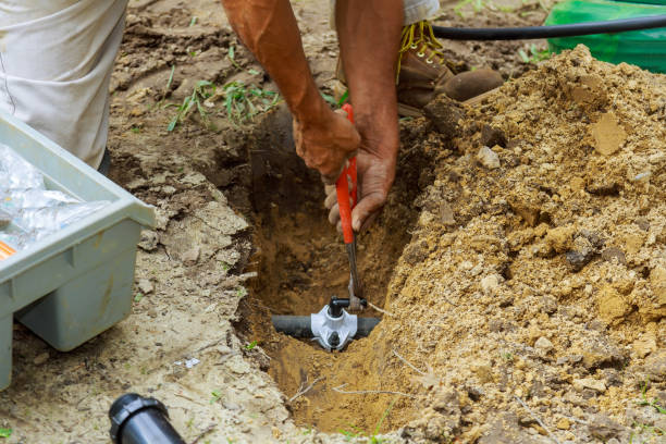 homme travaillant avec des tuyaux dans le sol lors de l’installation d’un nouveau système d’arrosage souterrain - tuyau darrosage photos et images de collection